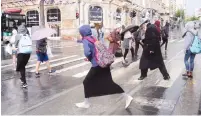  ?? (Marc Israel Sellem/The Jerusalem Post) ?? PEDESTRIAN­S COPE with a cloudburst in downtown Jerusalem yesterday.