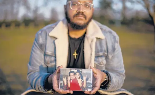  ?? ?? Adam Almonte holds a photograph of his older brother, Fernando Morales, while recalling how they used to share tuna sandwiches at this park in New York. Morales, 43, died April 7, 2020.