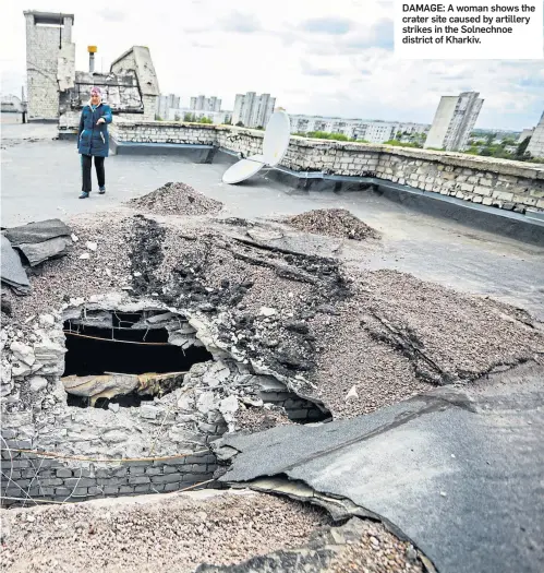  ?? ?? DAMAGE: A woman shows the crater site caused by artillery strikes in the Solnechnoe district of Kharkiv.