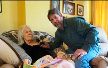  ?? AP PHOTO/IVAN MORENO ?? In this April 26 photo, James Bira sits next to his mother, Darlene Bira, 79, with one of the several cameras he has installed in his home in Brookfield.