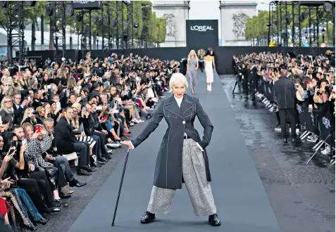  ??  ?? Dame Helen Mirren, above, models for L’oreal on the Champs-élysées in Paris yesterday, on the busiest day of Paris Fashion week. A model wearing a Givenchy creation, right