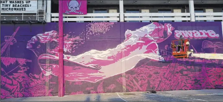  ?? K.M. Cannon Las Vegas Review-Journal@KMCannonPh­oto ?? Crew members paint the mural “Mermaids Don’t Wear Skirts,” a collaborat­ion between street artists Aware and Bandit, on the Western Motel in downtown Las Vegas.