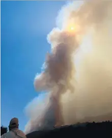  ??  ?? SMOKE obscures the sun as a U.S. Forest Service official watches the Whittier fire burn just north of Goleta.