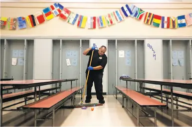  ?? Photos by Leah Millis / The Chronicle ?? Above: Head custodian Adam Zendejas sweeps the cafeteria floor between groups of students during lunchtime at Stoneman Elementary School in Pittsburg. Below: A student looks over the lunch offerings being served by Monica Rocha (left), assistant...