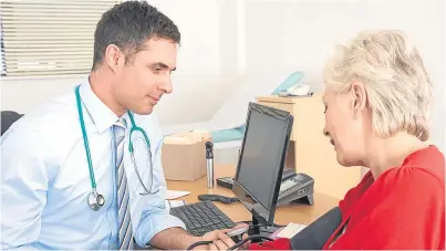  ??  ?? A doctor takes a woman’s blood pressure during a check-up.