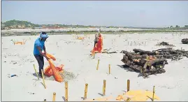  ??  ?? Workers removing shrouds covering graves at Shringverp­ur Ghat on Monday.