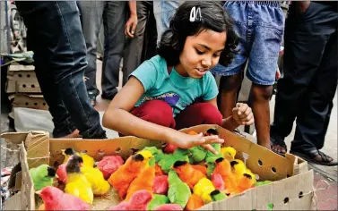  ??  ?? A child selects coloured, dyed chicks on sale at a roadside stall in Siliguri on Friday. AFP