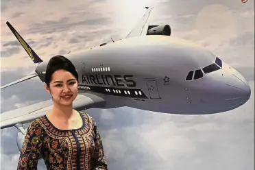  ?? AFP ?? Revenue push: An SIA stewardess poses in front of a poster of the SIA Airbus A380. After the planned revamp, the seat count in the Singapore Airlines A380s will rise by as much as 24% to 471 as the airline makes better use of the aircraft’s space...