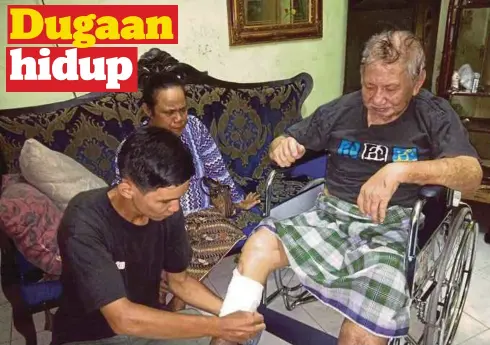  ??  ?? MOHD Azman membetulka­n balutan pada kaki bapanya, Mohd Imran di rumah mereka sambil diperhatik­an ibunya, semalam.