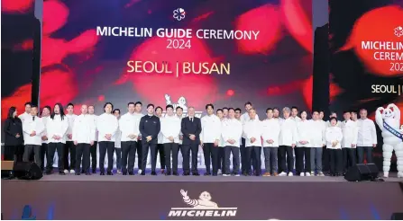  ?? Yonhap ?? Michelin Korea Managing Director Jerome Vincon, 17th from left, poses with chefs of restaurant­s in Seoul and Busan recognized by the Michelin Guide during an annual ceremony held in Busan, Feb. 22.
