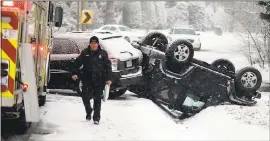 ?? STEVE HELBER — THE ASSOCIATED PRESS ?? A police officer walks from the scene of an overturned Jeep after an accident on a snowcovere­d road in Richmond, Va., on Wednesday. A winter storm made its way through the South, even down through the Gulf Coast.