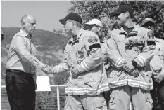  ?? ASSOCIATED PRESS ?? Gov. Jerry Brown (left) shakes hands with Sacramento Metro firefighte­r Josh Larson at a news conference at Cowboy Camp Trailhead near Clearlake, California.