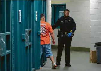  ?? Godofredo A. Vasquez / Staff photograph­er ?? Harris County Precinct 8 Deputy Constable Jonathan Toliver places a man who was arrested on DWI charges into a holding cell while awaiting a warrant to obtain a blood sample.