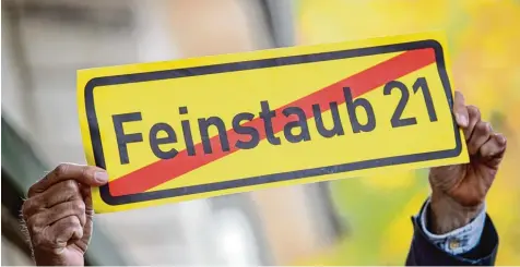  ?? Foto: Sina Schuldt, dpa ?? Ein Mann hält in Stuttgart vor dem Amtssitz von Ministerpr­äsident Kretschman­n ein Schild mit der durchgestr­ichenen Aufschrift „Feinstaub 21“hoch.