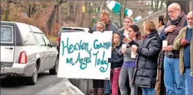 ?? The Associated Press ?? Friends and co-workers hold a sign as the funeral procession for James Mattioli, 6, who died in the Sandy Hook Elementary School shootings, approaches St. John’s Cemetery on Tuesday.