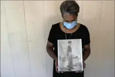  ?? Gerald Herber/Associated Press ?? Belvin Jefferson White holds a portrait of her father, Saymon Jefferson, who died of COVID-19 on May 18 in Baton Rouge, La. Ms. White’s uncle also died of the disease.