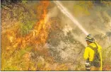  ?? Will Lester The Associated Press ?? A firefighte­r puts out a hot spot along Highway 38 northwest of Forrest Falls, Calif., as the El Dorado Fire continues to burn Thursday afternoon.