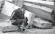  ?? LEO CORREA AP Photo ?? A rescue worker takes a break on Sept. 28 as he sits on the debris at the scene where a woman was found dead after a Russian attack that heavily damaged a school in Mykolaivka, Ukraine.