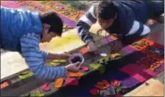 ?? GIOVANNA DELL’ORTO VIA AP ?? Two young men putting the finishing touches on an elaborate sawdust pattern created on top of a cobbleston­e street in Antigua, Guatemala. About 12 kilometers (7.5 miles) of streets in the Central American city are covered with flower and sawdust...