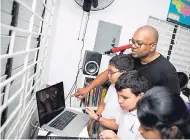  ??  ?? DJ Denvo delves into the art of mixing with Reach Academy students Zachary Harrison (left) and Connor Weston (centre) - both 10 years old – and seven-year old Suhavi Kumar during a recent weekly Kids Mix DJ Club at the school.