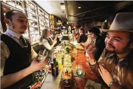  ?? DAMIAN DOVARGANES / AP ?? Bar Manager Evan Roth (left) talks to fellow bartender Roland Gonzalez, while tasting bourbon at the Seven Grand bar, a whiskey bar in Los Angeles. Seven Grand offers a selection of more than 700 whiskies from around the world.