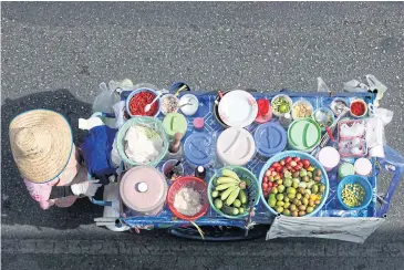  ?? SEKSAN ROJJANAMET­AKUN ?? A vendor pushes a somtam cart along the road near Victory Monument in Bangkok. The sluggish economic recovery and effects of the drought are among the factors driving down consumer confidence, according to the latest UTCC study.