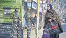  ?? PTI ?? A woman walks past security personnel during a shutdown in Srinagar on Tuesday.