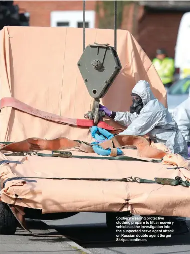  ??  ?? Soldiers wearing protective clothing prepare to lift a recovery vehicle as the investigat­ion into the suspected nerve agent attack on Russian double agent Sergei Skripal continues