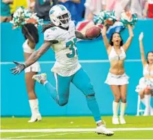  ??  ?? Dolphins free safety Walt Aikens returns a blocked Cardinals’ extra point attempt to score 2 points for Miami in a crucial fourth-quarter play.