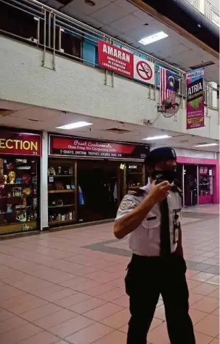  ?? PIC BY MUHAMMAD ASYRAF SAWAL ?? A security guard making his rounds at a deserted shopping mall in Shah Alam on Saturday.