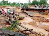  ?? PTI ?? Villagers walk on the washed out road after heavy rains near Deesa city in Gujarat on Wednesday. —