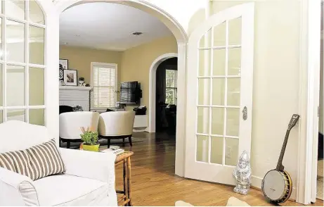  ?? Gary Fountain photos ?? French doors open up the space between Paula Murphy’s living room and the sunroom. Propped against the wall is a banjo that belonged to Murphy’s father; standing by the door is a mirrored garden gnome she received as a gift.