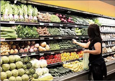  ?? Bloomberg News/DANIA MAXWELL ?? A customer selects cucumbers during the grand opening of a Whole Foods Market in Burbank, Calif., in June.