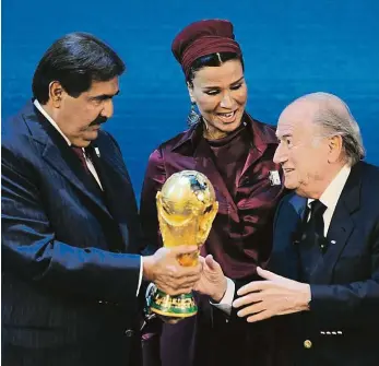  ?? Foto: Profimedia.cz ?? Je to vaše! Expreziden­t FIFA Sepp Blatter předává emírovi Hamadovi bin Chalífovi Ál Thánímu (vlevo) trofej pro vítěze MS. Katar jako první země z Blízkého východu uspořádá fotbalový světový šampionát.