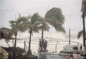  ?? REUTERS PIC ?? People standing next to swaying palm trees as Tropical Storm Lidia hits Los Cabos, Mexico, on Thursday.