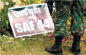  ?? (AP FOTO) ?? STILL CRYING FOR JUSTICE. A Philippine National Police Special Action Force commando stands near a tarpaulin poster calling for justice to the 44 commandos killed in a clash with Moro rebels following a two-day wake on Jan. 31, 2015 at Camp Bagong Diwa...