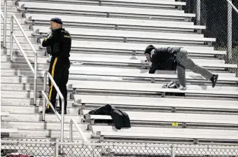  ?? Edward Lea / Associated Press ?? Police search the stands after a shooting Friday during a football game at Pleasantvi­lle High School in Pleasantvi­lle, N.J. Three people were injured, including a 10-year-old, officials said.