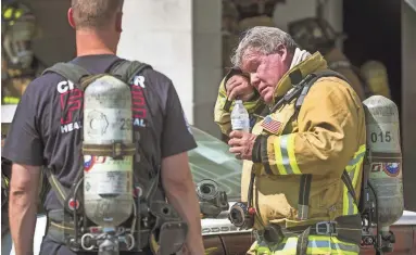  ?? TOM TINGLE/THE REPUBLIC ?? Chandler Fire Capt. Kent Keller, right, wipes away sweat during a big-box drill at the training academy in Chandler. Capt. Allen Blaine is at left.