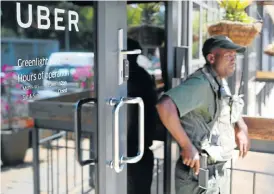  ?? /Reuters ?? On guard: A private security guard stands outside Uber’s Johannesbu­rg offices. Uber and Taxify drivers have been under violent attack since the app-based services gained popularity.