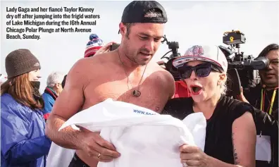  ??  ?? Lady Gaga and her fiancé Taylor Kinney dry off after jumping into the frigid waters of Lake Michigan during the 16th Annual Chicago Polar Plunge at North Avenue Beach, Sunday.