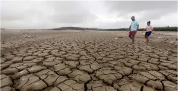  ??  ?? File photo shows a family negotiatin­g their way through caked mud around a dried up section of the Theewaters­kloof dam near Cape Town. — Reuters photo