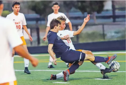  ?? GABRIELA CAMPOS/NEW MEXICAN FILE PHOTOS ?? Santa Fe High senior Matt Hunter races against Taos’ Ricky Nichols to possess the ball during a Sept. 18 nondistric­t match. The Demons play their first postseason game in six years Friday when they face Clovis in the state soccer tournament.