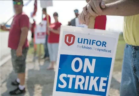  ??  ?? Employees and Unifor members hold “On Strike” signs outside the General Motors Co. plant in Ingersoll, Ont., Wednesday in a dispute over job security. Job security remains the key sticking point between the company and Unifor Local 88.