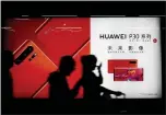  ?? ASSOCIATED PRESS ARCHIVES ?? Commuters walk by a Huawei P30smartph­one ad in Beijing. The White House is trying to lower expectatio­ns for any ‘big announceme­nt’ from this week’s trade talks.