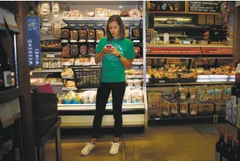  ?? Lea Suzuki / The Chronicle 2014 ?? Instacart personal shopper Sydney Hollingswo­rth looks over a customer’s order at the Bi-Rite Market on Divisadero Street in San Francisco in 2014.