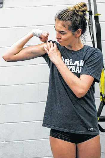  ??  ?? Sophomore outside hitter Kiana Fallaha shows off her biceps during a weight training session at Harlan. The team underwent grueling conditioni­ng and weight-training exercises in a short amount of time.