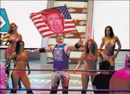  ?? EDUARDO VERDUGO/ THE ASSOCIATED PRESS ?? Pro wrestler Sam Polinsky waves an American flag emblazoned with a photo of President Donald Trump on Sunday in Mexico City. Polinsky says taking on the persona of a Trump supporter is an unparallel­ed chance to play the ultimate villain to Mexican fans.