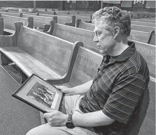  ?? CLARA PASIEKA — LOCAL JOURNALISM INITIATIVE ?? Rev. Richard Jackson looks over a historical photo from First Moncton Baptist Church which served as an emergency hospital during the Spanish Flu pandemic a century ago.