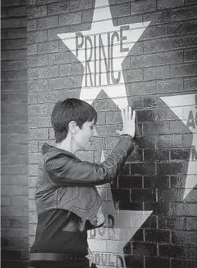  ?? Elizabeth Flores/Star Tribune via AP ?? Phyllis Foundis places her hand on a Prince memorial wall on First Avenue on Friday in Minneapoli­s, Minn. Foundis traveled from Australia to commemorat­e the first anniversar­y of the superstar singer's death. She will share the experience on her blog,...