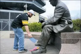 ?? Lake Fong/Post-Gazette ?? Robert Turner, 31, of Fox Chapel places a card Friday at the Art Rooney Sr. statue outside Heinz Field to pay his respects to Steelers chairman Dan Rooney, who died Thursday. Mr. Turner wrote “Thanks for the memory, thanks for the champions” on the card.